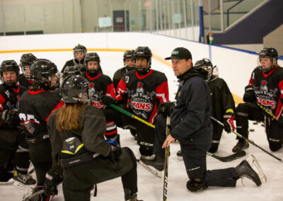 A coach giving instructions to his team on the ice during a hockey game.