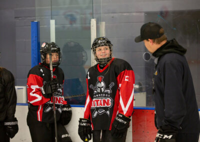 A coach conversing with young girls in hockey uniforms, fostering teamwork and skill development.
