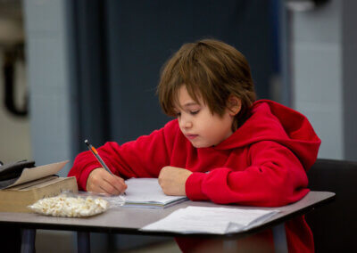 Child jotting down notes in notebook.